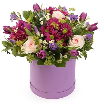 Arrangement in a hat box of seasonal flowers.